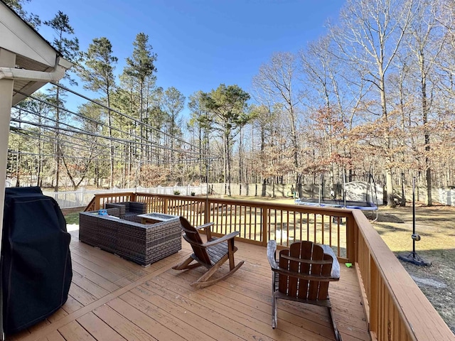 wooden deck featuring an outdoor living space, a trampoline, and a grill