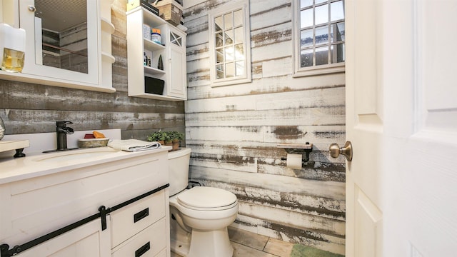 bathroom with toilet, vanity, tile patterned flooring, and wooden walls