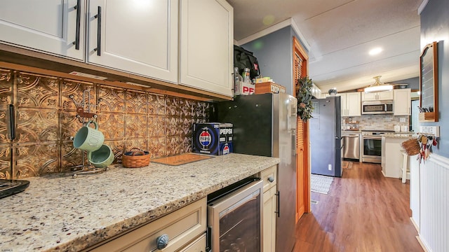 kitchen featuring dark wood-type flooring, stainless steel appliances, light stone counters, decorative backsplash, and beverage cooler