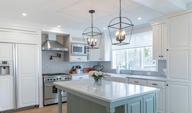 kitchen with wall chimney range hood, built in appliances, white cabinetry, and a kitchen island