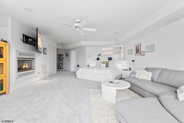 living room with a ceiling fan, a glass covered fireplace, and carpet