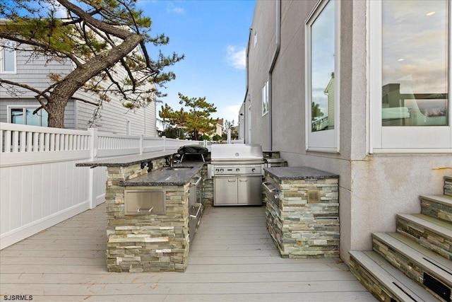 wooden terrace with fence, exterior kitchen, and a sink