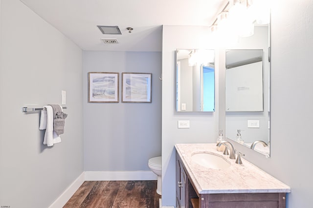 bathroom featuring baseboards, visible vents, toilet, wood finished floors, and vanity