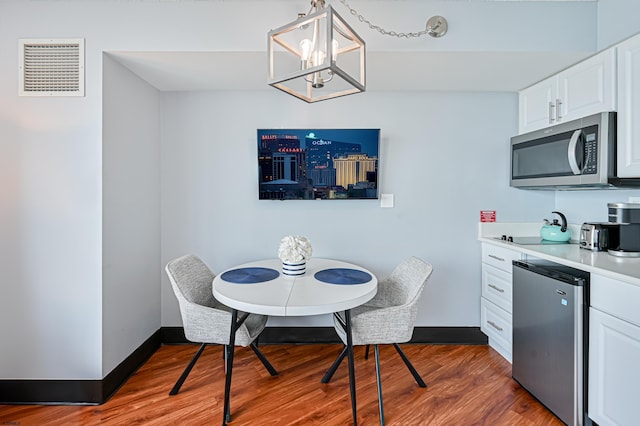 kitchen featuring refrigerator, light countertops, stainless steel microwave, visible vents, and white cabinets