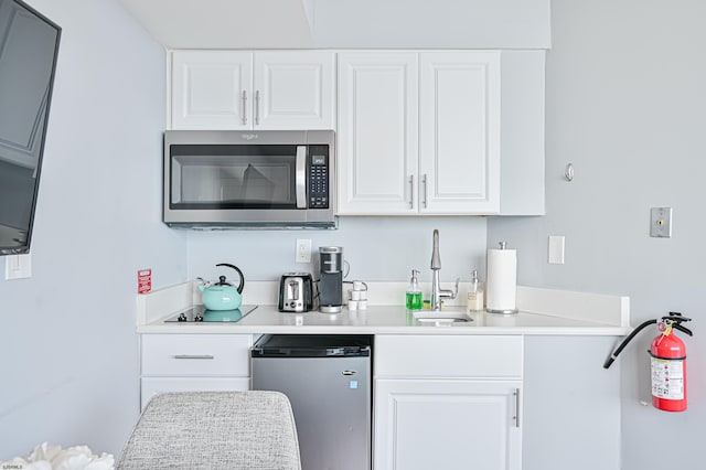 kitchen with white cabinets, a sink, stainless steel appliances, and light countertops