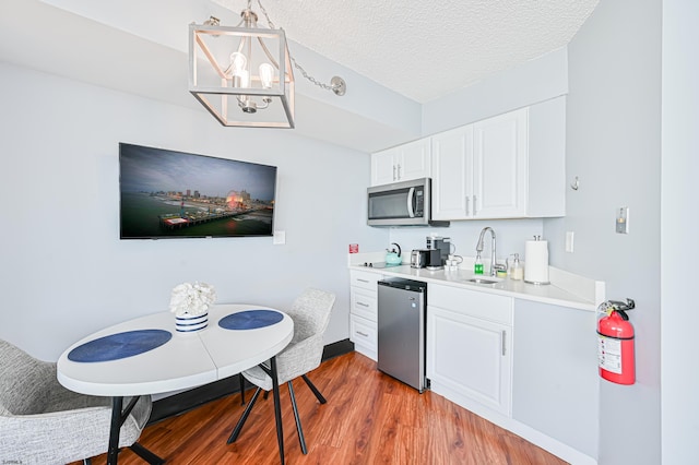 kitchen featuring decorative light fixtures, stainless steel appliances, light countertops, white cabinets, and a sink