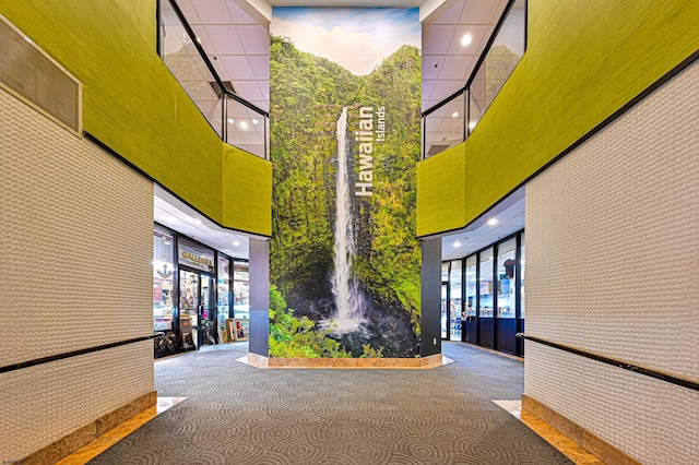 interior space with expansive windows, a towering ceiling, and wallpapered walls