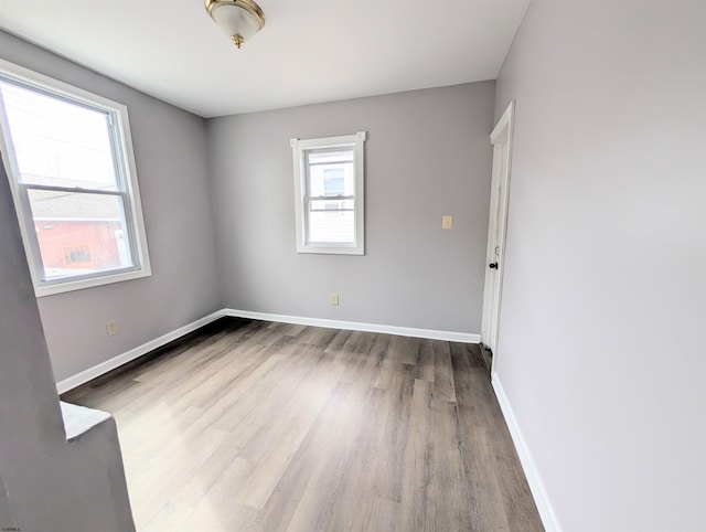 empty room with baseboards, light wood-style flooring, and a healthy amount of sunlight