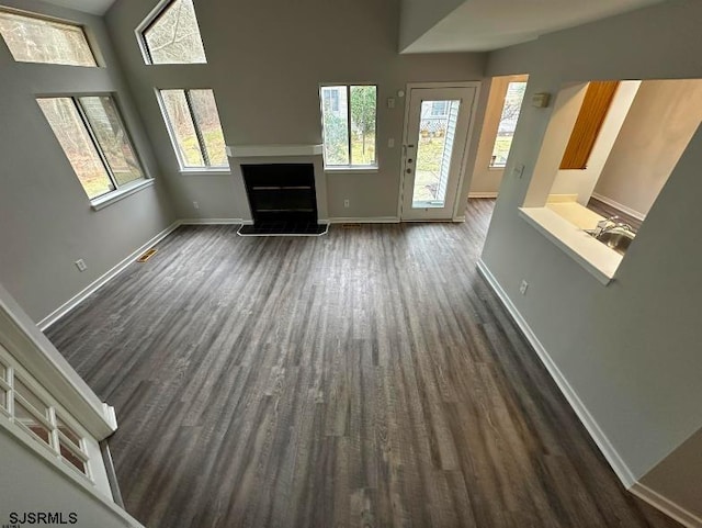 unfurnished living room with dark wood-style floors, a fireplace with raised hearth, and baseboards