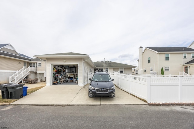 view of front facade with an attached garage, an outdoor structure, fence, stairs, and driveway