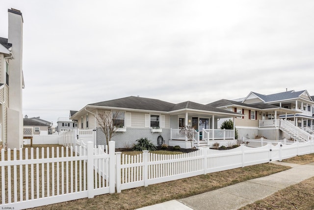 view of front of home with covered porch, brick siding, and a fenced front yard