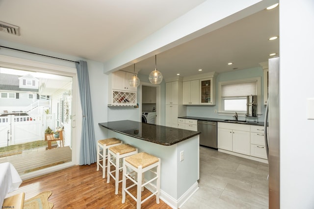 kitchen featuring a kitchen breakfast bar, stainless steel appliances, glass insert cabinets, and white cabinetry