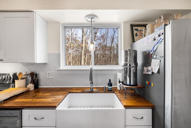 kitchen featuring wood counters, white cabinets, backsplash, freestanding refrigerator, and dishwasher