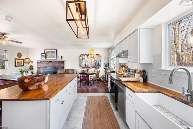 kitchen with butcher block counters, white cabinetry, a kitchen island, and a sink