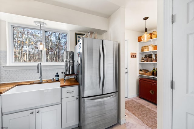 kitchen featuring pendant lighting, open shelves, wooden counters, freestanding refrigerator, and a sink