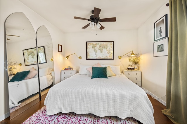 bedroom with a ceiling fan, baseboards, arched walkways, and dark wood-style flooring