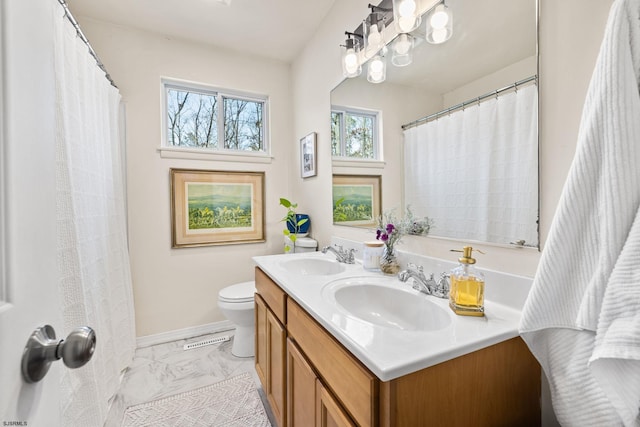 full bathroom featuring double vanity, marble finish floor, toilet, and a sink