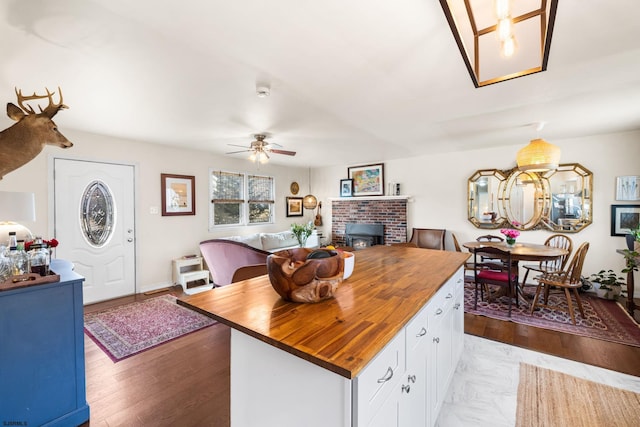 kitchen featuring light wood-style flooring, open floor plan, white cabinets, a kitchen island, and butcher block countertops