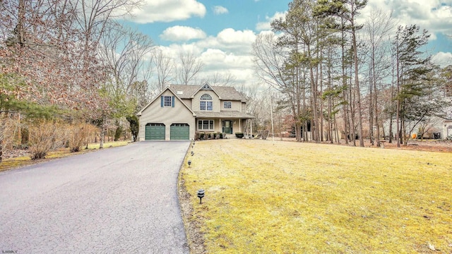 view of front of house featuring an attached garage, a porch, aphalt driveway, and a front yard