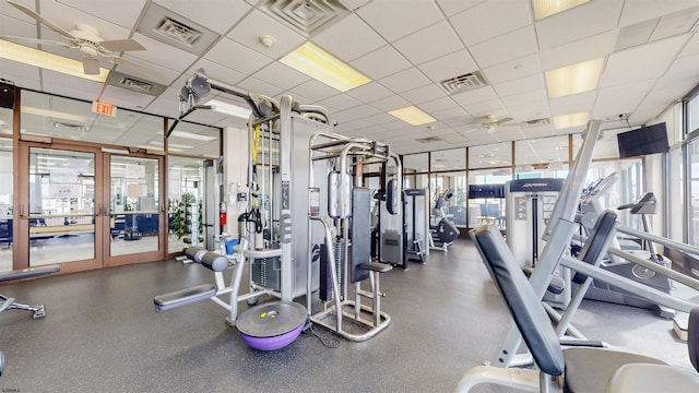 exercise room with a paneled ceiling, visible vents, and a ceiling fan