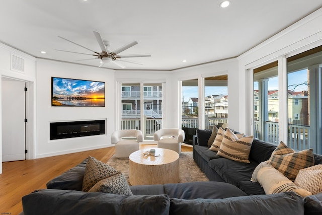 living room featuring ceiling fan, recessed lighting, wood finished floors, visible vents, and a glass covered fireplace