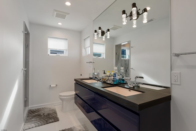 bathroom with double vanity, a sink, toilet, and baseboards