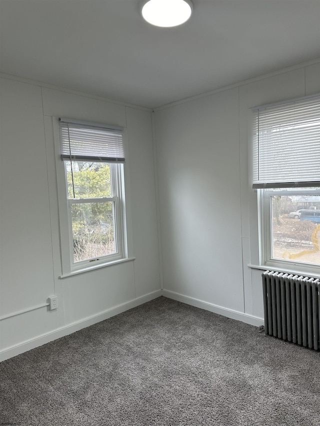 spare room with carpet floors, baseboards, and radiator heating unit