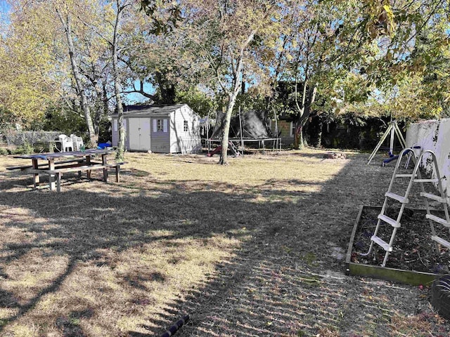 view of yard featuring a trampoline, a playground, fence, a shed, and an outdoor structure