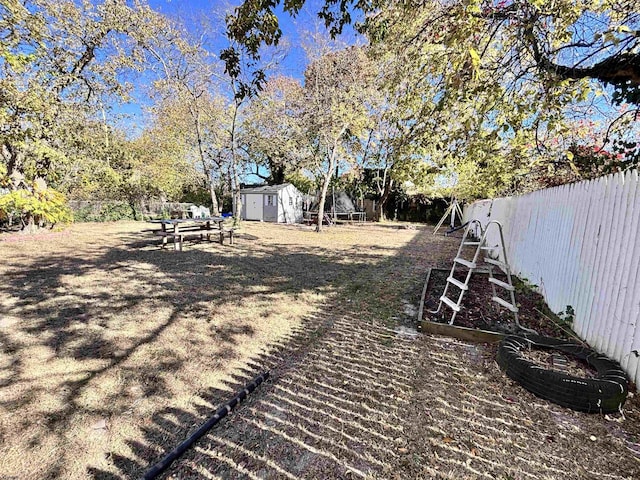 view of yard with a shed, an outdoor structure, and a fenced backyard