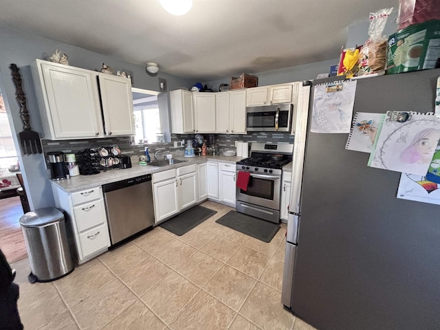 kitchen featuring stainless steel appliances, a sink, white cabinets, light countertops, and tasteful backsplash