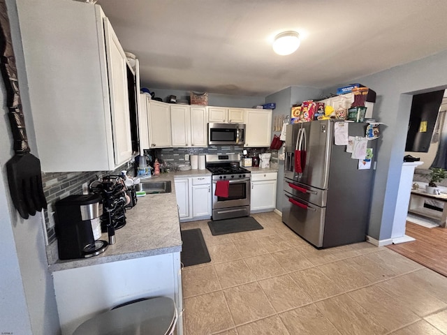 kitchen featuring stainless steel appliances, light countertops, decorative backsplash, and white cabinetry