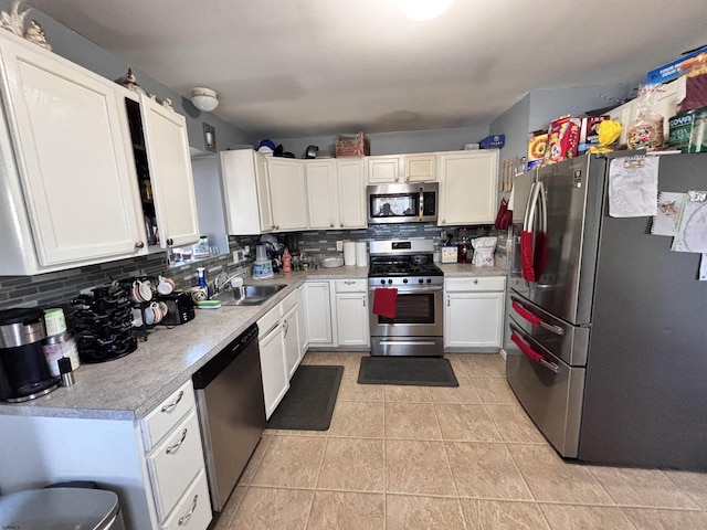 kitchen with stainless steel appliances, a sink, white cabinetry, light countertops, and backsplash