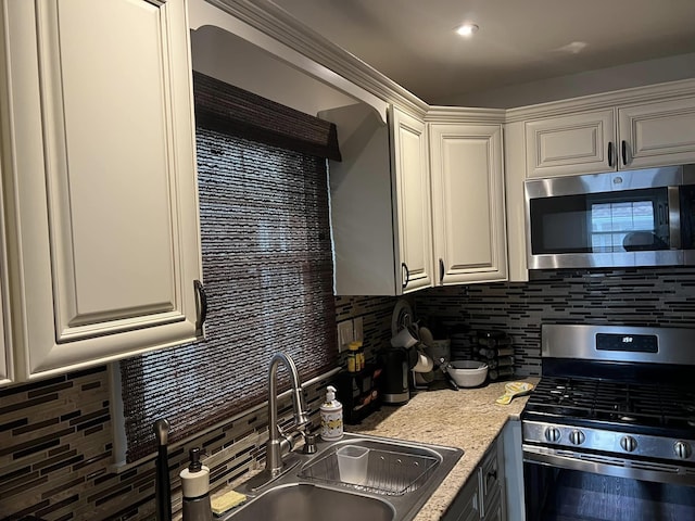 kitchen with stainless steel appliances, white cabinets, a sink, and decorative backsplash