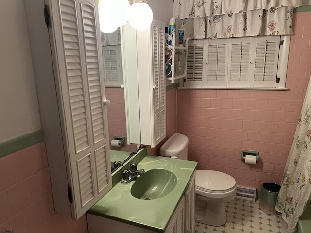 bathroom featuring toilet, tile walls, and vanity