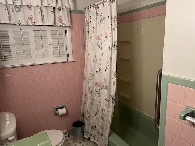 full bathroom with toilet, wainscoting, shower / bath combo with shower curtain, and tile walls