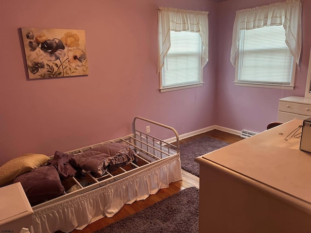 bedroom featuring baseboards, baseboard heating, and wood finished floors