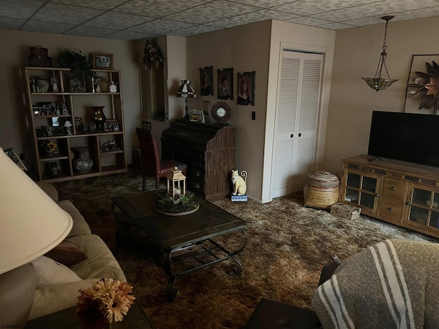 living area with carpet floors and a drop ceiling