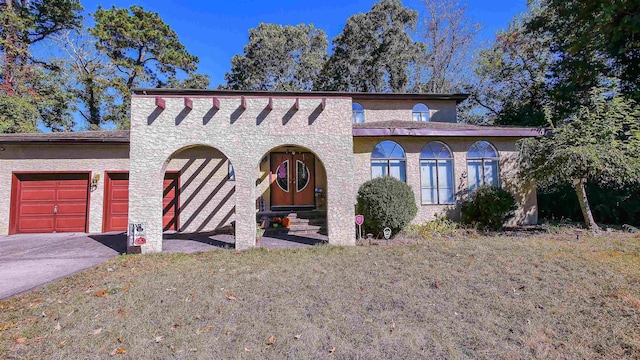 mediterranean / spanish-style house featuring driveway, an attached garage, a front yard, and stucco siding