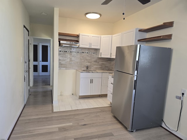 kitchen with white cabinets, light countertops, light wood-type flooring, freestanding refrigerator, and open shelves