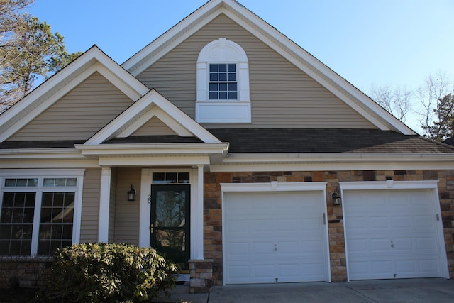 view of front of property featuring stone siding, roof with shingles, and driveway