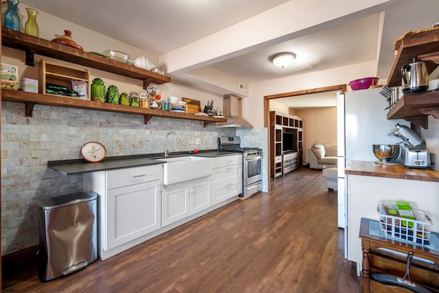 kitchen with stainless steel gas stove, dark countertops, white cabinetry, open shelves, and a sink