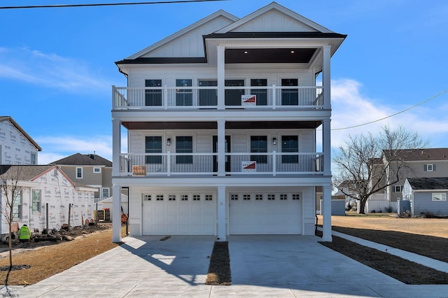 coastal inspired home featuring a balcony, a garage, board and batten siding, and concrete driveway