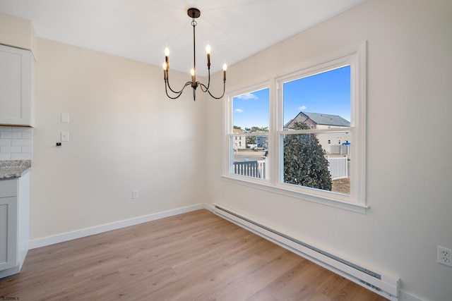 unfurnished dining area with a baseboard radiator, baseboards, light wood finished floors, and an inviting chandelier