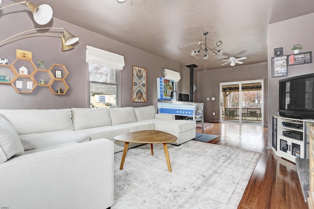 living area featuring dark wood-style floors, a wood stove, and a ceiling fan