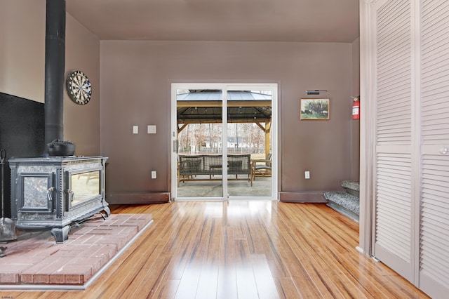 unfurnished living room featuring light wood-style flooring, a wood stove, and baseboards