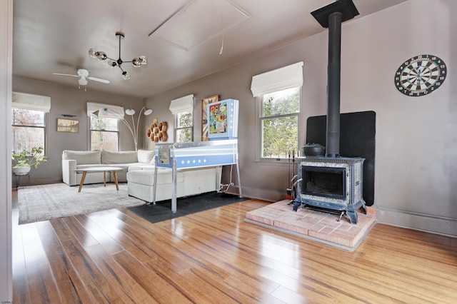 living area featuring plenty of natural light, wood finished floors, a wood stove, and attic access