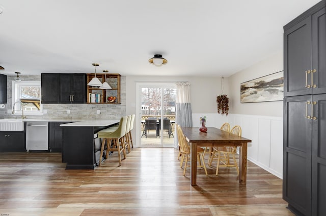 dining space with a wealth of natural light, a wainscoted wall, and light wood finished floors