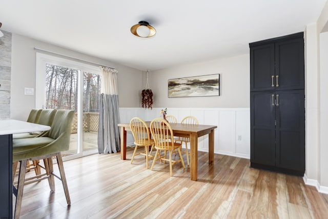 dining area featuring light wood-type flooring and a wainscoted wall