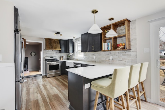 kitchen featuring a peninsula, premium range hood, light countertops, appliances with stainless steel finishes, and backsplash