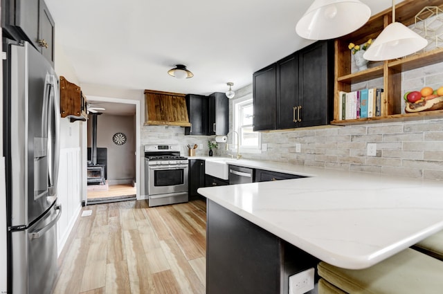 kitchen with light stone counters, a peninsula, appliances with stainless steel finishes, open shelves, and decorative light fixtures